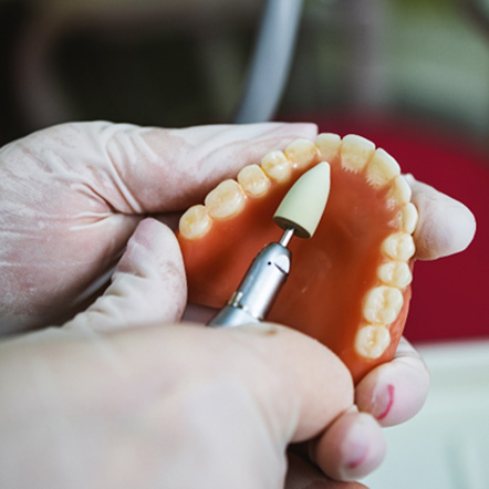Lab technician filing dentures