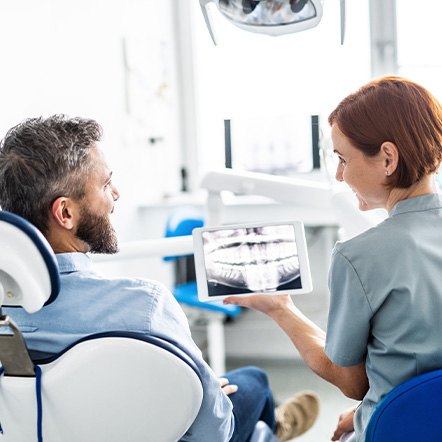A dental patient holding an enlarged dental implant model