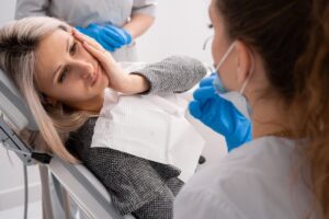 Woman experiencing emergency in dentist's chair.